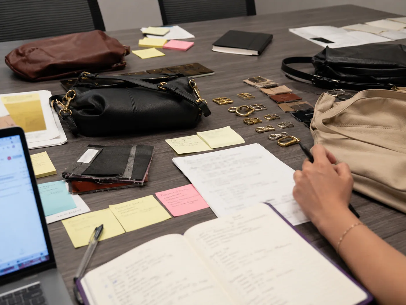 Smartphone-style sourcing desk comparing factory audit printouts, quote sheets, sample bag, and trim tray