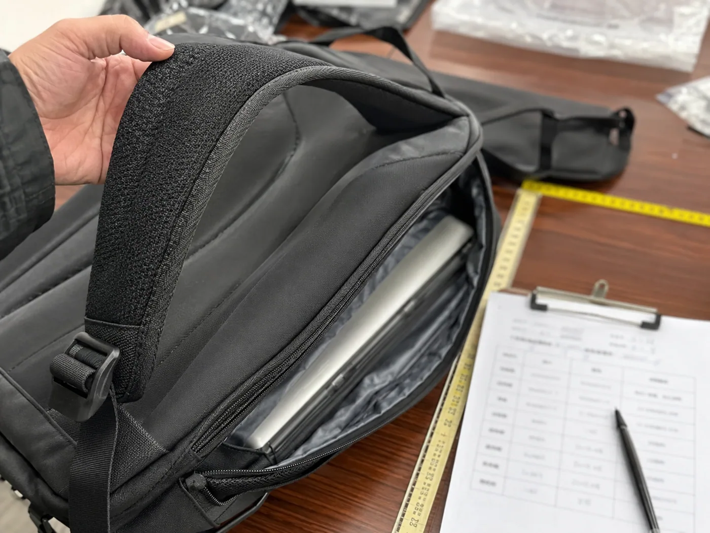 Smartphone-style backpack feature check with padded strap, buckle, laptop pocket, zipper seam, measuring tape, and checklist