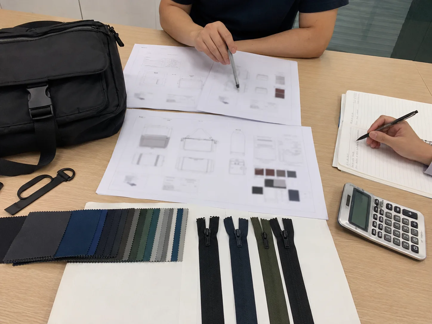 Bag manufacturing RFQ review desk with tech pack, swatches, and trim samples